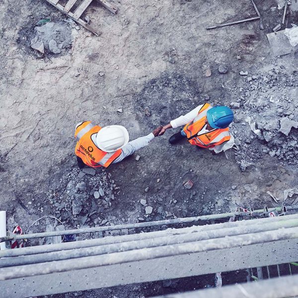 Octavius Shot of two builders shaking hands at a construction site